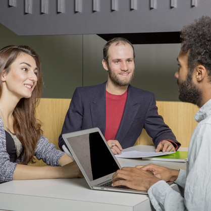 Three students sit opposite each other and they are talking.